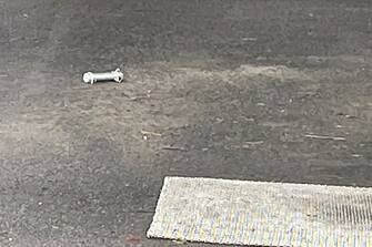 A cylinder-shaped object (L), believed to have been thrown during Japan's Prime Minister Fumio Kishida's campaign, is seen on the ground in Wakayama on April 15, 2023. - Kishida was evacuated from a port in Wakayama after a blast was heard, but he was unharmed in the incident, local media reported on April 15. (Photo by JIJI Press / AFP) / Japan OUT (Photo by STR/JIJI Press/AFP via Getty Images)