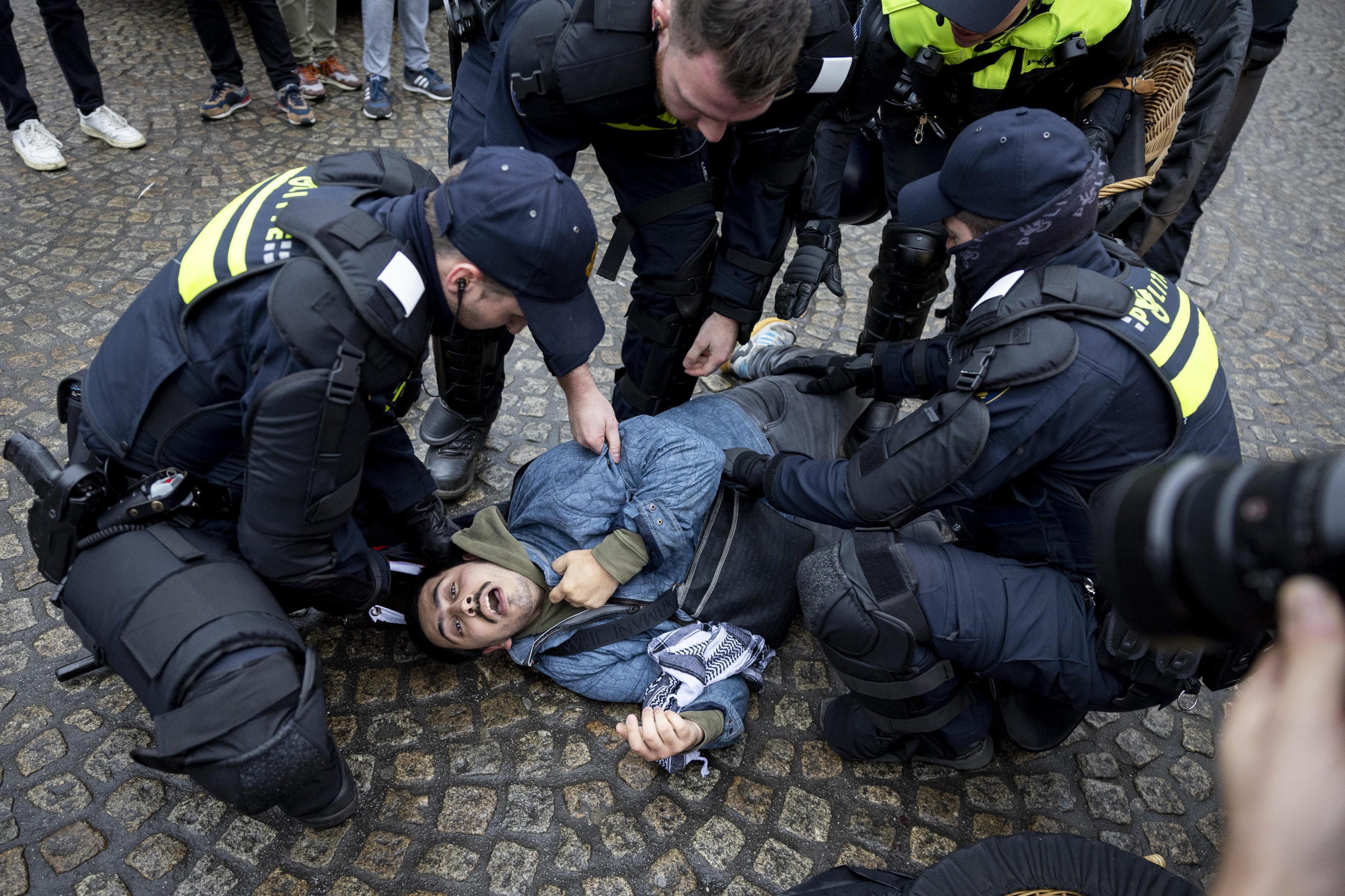 epa11713056 A pro-Palestinian protester lies on the ground surrounded by Dutch police on Dam Square in Amsterdam, the Netherlands, 10 November 2024. The protest took place while an emergency ordinance and demonstration ban are in place in the city. These measures were previously deployed following tensions and violence involving supporters of Israeli soccer club Maccabi Tel Aviv after a soccer match at Ajax on 07 November 2024.  EPA/ROBIN VAN LONKHUIJSEN