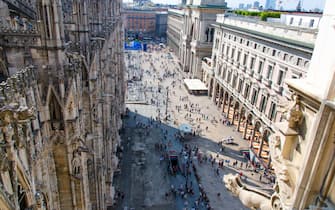 Crowd of small figures of many people are walking on Piazza del Duomo square near Gallery Vittorio Emanuele II in historical city centre, top view fro