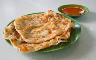 Singapore - December 1, 2019: 2 pieces of Roti Prata or Roti Canai on a plate with a plate of curry soup