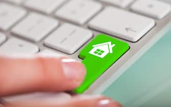 Close-up Of Hand Over Green Key With House Sign On Keyboard