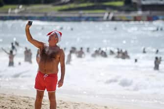 epa11043520 A man in a Santa hat takes a selfie on Christmas Day at Bondi Beach in Sydney, Australia, 25 December 2023.  EPA/STEVEN SAPHORE AUSTRALIA AND NEW ZEALAND OUT