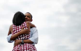 First Lady Michelle Obama (L) and US President Barack Obama (R) hug after delivering remarks during a campaign event at the Alliant Energy Amphitheater in Dubuque, Iowa, August 15, 2012, during his three-day campaign bus tour across the state.      AFP PHOTO/Jim WATSON (Photo by JIM WATSON / AFP)