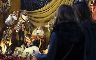 Due donne guardano la vetrina di un negozio di articoli religiosi che espone un presepe con i Re Magi che indossano la mascherina, Roma, 16 dicembre 2020.   MAURIZIO BRAMBATTI/ANSA
