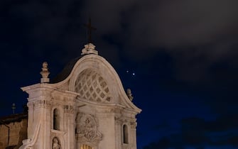 Planets Jupiter and Venus in conjunction are seen after sunset behind Santa Maria del Suffragio (Holy Souls) church in LAquila, Italy, on march 1st, 2023. Planets seem to be very close (less than a degree away from each other). Moons (satellites) of Jupiter are visible even with a telephoto lens. (Photo by Lorenzo Di Cola/NurPhoto via Getty Images)