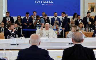 Papa Francesco al G7 Pope Francis (C) flanked by French President Emmanuel Macron (L) and Italy's Prime Minister Giorgia Meloni (R), and US President Joe Biden (bottom, back turned) take part in a working session on Artificial Intelligence (AI), Energy, Africa-Mediterranean at the Borgo Egnazia resort during the G7 Summit in Savelletri near Bari, Italy, on June 14, 2024. (Photo by Ludovic MARIN / AFP)
