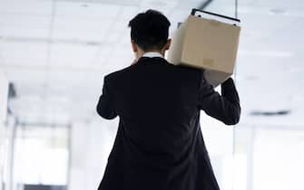 Fired businessman carrying box of personal items