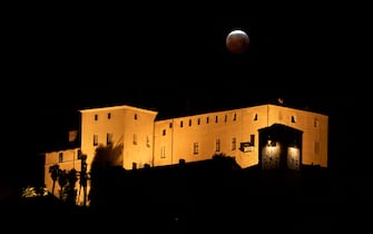The so-called Super Blood Wolf Moon starts exits Earth's dark umbral shadow during a total lunar eclipse over the "Castello della Manta" in Manta, near Cuneo, northwestern Italy on January 21, 2019. - An unusual set of celestial circumstances comes together on january 20 for skywatchers in Europe, Africa and the Americas, where a total lunar eclipse may be glimpsed, offering a view of a large, red Moon. (Photo by MARCO BERTORELLO / AFP)        (Photo credit should read MARCO BERTORELLO/AFP via Getty Images)