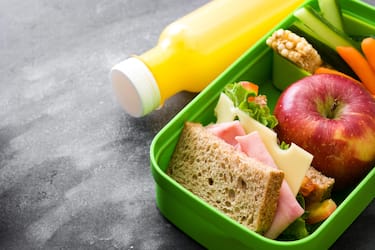 Healthy school lunch box: Sandwich, vegetables ,fruit and juice on black stone