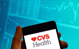 CHINA - 2023/02/15: In this photo illustration, the American healthcare company that owns CVS Pharmacy, CVS Health, logo is seen displayed on a smartphone screen with an economic stock exchange index graph in the background. (Photo Illustration by Budrul Chukrut/SOPA Images/LightRocket via Getty Images)