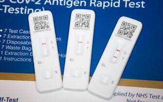 Two positive results and a single negative test result. Three Lateral flow test / LFT / LFD / lateral flow devices kits / device kit, two of which have tested positive (showing two red lines) for COVID 19 virus coronavirus during antigen home testing, in London. UK. To show positive, two red lines will appear. One test shows the positive line to be feint / faint. The third test showing one line only is a negative test. The test (by Flowfex made in China) has detected virus in the sample nasal swab taken from the nose. (128)