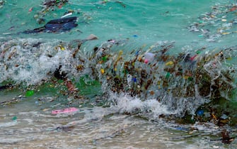 TOPSHOT - A wave carrying plastic waste and other rubbish washes up on a beach in Koh Samui in the Gulf of Thailand on January 19, 2021. (Photo by Mladen ANTONOV / AFP) (Photo by MLADEN ANTONOV/AFP via Getty Images)