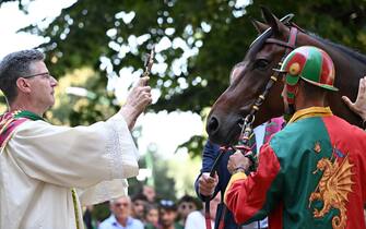 Italian jockey Andrea Coghe , also known as  Tempesta  and the horse Vitzichesu running for the 'Drago' contrada, a district of the city, is blessed by a local priest at the contrada's church, ahead of the historical Italian horse race 'Palio di Siena' in Siena, Italy, 16 August  2023. The traditional horse races between the Siena city districts will be held 02 July as the 'Palio di Provenzano' on the holiday of the Madonna of Provenzano and on 16 August as the 'Palio dell'Assunta' on the holiday of the Virgin Mary.
ANSA/CLAUDIO GIOVANNINI