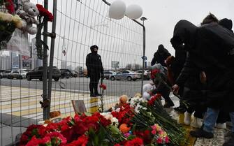 People lay flowers at a makeshift memorial in front of the Crocus City Hall, a day after a gun attack in Krasnogorsk, outside Moscow, on March 23, 2024. Camouflaged assailants opened fire at the packed Crocus City Hall in Moscow's northern suburb of Krasnogorsk on March 22, 2024, evening ahead of a concert by Soviet-era rock band Piknik in the deadliest attack in Russia for at least a decade. Russia on March 23, 2024, said it had arrested 11 people - including four gunmen - over the attack on a Moscow concert hall claimed by Islamic State, as the death toll rose to over 100 people. (Photo by Olga MALTSEVA / AFP) (Photo by OLGA MALTSEVA/AFP via Getty Images)
