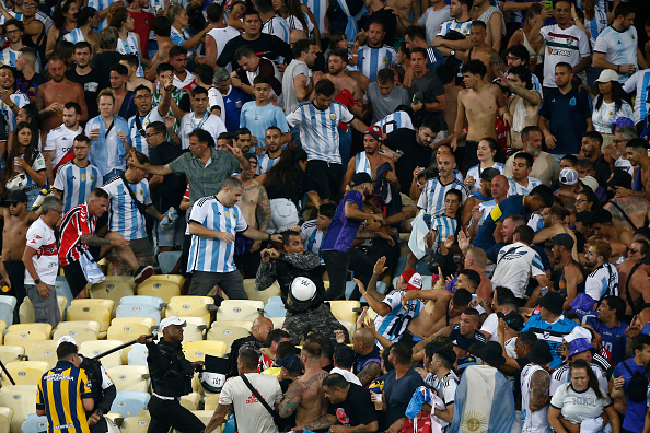 RIO DE JANEIRO, BRAZIL - NOVEMBER 21: Police officers armed with batons clash with fans as the match is delayed due to the incidents prior to a FIFA World Cup 2026 Qualifier match between Brazil and Argentina at Maracana Stadium on November 21, 2023 in Rio de Janeiro, Brazil. (Photo by Wagner Meier/Getty Images)