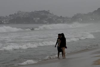 Persone sulla spiaggia di Acapulco, in Messico, attendono l'arrivo dell'uragano Otis