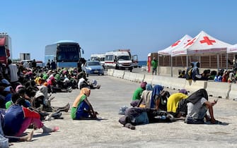 Dall'hotspot all'area di presidio dei vigili del fuoco, 400 forse 500 metri di strada - in contrada Imbriacola a Lampedusa - ricolmi di coperte termiche, scarpe, bottigliette d'acqua vuote, indumenti e tovaglie, dove aleggia un odore nauseabondo. E' un "mare umano" - scortato dai volontari della Croce Rossa - quello che anche stamattina è stato spostato perché è proprio dall'area dei vigili del fuoco che i migranti vengono caricati sugli autobus per raggiungere il porto dove verranno imbarcati su navi militari e traghetti di linea, 14 settembre 2023. ANSA/ELIO DESIDERIO