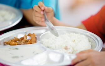 Cute asian kid boy eating foods by self. Child holding a spoon. Selective focus. Copy space. Kid enjoy eating.