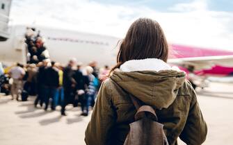 Young woman is on an airport runway, ready to board the plane