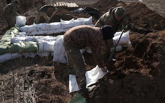 Ukrainian servicemen prepare earthbags to build a fortification not far from town of Avdiivka in the Donetsk region, amid the Russian invasion of Ukraine, on February 17, 2024. (Photo by Anatolii STEPANOV / AFP)