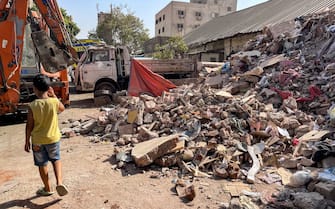 A boy walks past rubble near an excavator at the scene of a building collapse in the Hadayiq al-Qubba district of Cairo on July 17, 2023. (Photo by Ahmed HASAN / AFP) (Photo by AHMED HASAN/AFP via Getty Images)