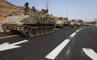 Israeli soldiers in an armoured vehicles drive along a street near northern town of Kiryat Shmona close to the border with Lebanon on October 9, 2023. Israel also came under attack from the north when Lebanon's Hezbollah launched guided missiles and artillery shells on October 8 "in solidarity" with Hamas, without causing any casualties. (Photo by JALAA  MAREY / AFP)