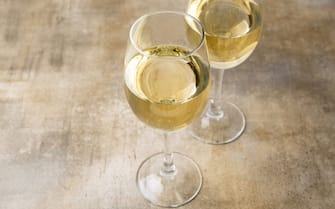 Two glasses of white wine, close up. Wine glasses on a brown background with copy space