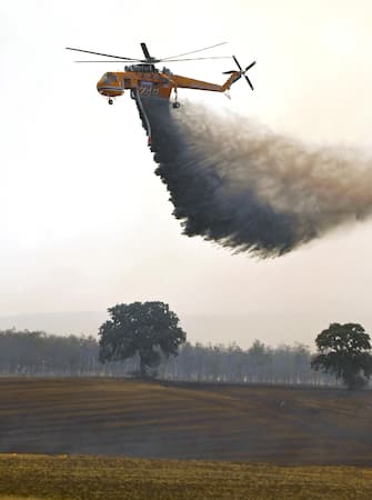 epa10811579 A firefighting helicopter drops water to extinguish a wildfire in the Avanta area, near Egnatia Odos motorway, in Alexandroupolis, Thrace, northern Greece, 21 August 2023. The wildfire that broke out early on 19 August in a forest in the Melia area of Alexandroupolis has spread rapidly due to the strong winds blowing in the area and is raging uncontrolled.The major wildfire in Alexandroupolis continues with unabated intensity for the third consecutive day. According to the Fire Department, the fire is difficult to be contained due to the strong winds in the area.  EPA/DIMITRIS ALEXOUDIS