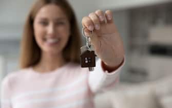 Happy house buyer woman holding keys at camera