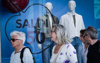 persone che camminano davanti a una vetrina con saldi