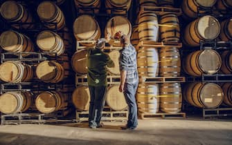 Caucasian men examining barrel in distillery