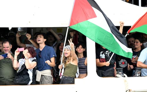 People aboard a boat wave Palestinian flags as they arrive to take part in a demonstration in support of Gaza and Palestinian people at Venice Lido during the 82nd Venice International Film Festival, on August 30, 2025. (Photo by Stefano RELLANDINI / AFP)