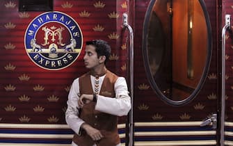 An Indian railway assistant checks his watch as he stands beside the "Maharajas' Express", India's first pan-India super luxury train, prior to its departure for Delhi from Kolkata on March 20, 2010.  The super luxury train costs some 800 US per night per person and was flagged off by Railways Minister Mamata Banerjee from the station in Kolkata.  AFP PHOTO/Deshakalyan CHOWDHURY (Photo credit should read DESHAKALYAN CHOWDHURY/AFP via Getty Images)