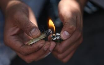 epa09368417 A man lights a marijuana cigarette at a Cannabis camp, outside the Supreme Court of Justice in Mexico City, Mexico, 26 July 2021.  A month after the historic ruling of the Mexican Supreme Court that lifted the prohibition of recreational marijuana use, recreational cannabis remains in a confused legal limbo, since it is still penalized in the Penal Code and the Government has not yet granted permits for self-consumption.  EPA/Sáshenka Gutiérrez