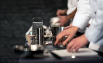 Team of professional chefs preparing food in a commercial kitchen. Cooks in the production process of system catering. An inside view of a pro caterin