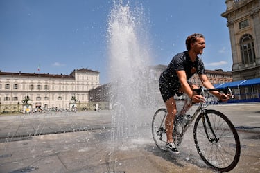 TURIN, ITALY - JULY 11: A man rides a bicycle inside a fountain in Piazza Castello on July 11, 2023 in Turin, Italy. The record for the highest temperature in European history was broken in August 2021, when 48.8C was registered in Floridia, a town in Italy's Sicilian province of Syracuse. (Photo by Stefano Guidi/Getty Images)
