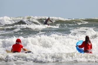 A surfer dressed as Santa gets out of the water after riding waves during the 15th annual "Surfing Santas" event in Cocoa Beach, Florida, on December 24, 2023. (Photo by Eva Marie UZCATEGUI / AFP) (Photo by EVA MARIE UZCATEGUI/AFP via Getty Images)