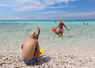 Boy dressing snorkel and mother on the beach