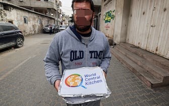 A man carries food aid packages provided by the non-profit non-governmental organisation World Central Kitchen, in Rafah in the southern Gaza Strip on March 17, 2024, amid the ongoing conflict between Israel and the militant group Hamas. (Photo by MOHAMMED ABED / AFP)