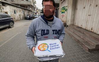 A man carries food aid packages provided by the non-profit non-governmental organisation World Central Kitchen, in Rafah in the southern Gaza Strip on March 17, 2024, amid the ongoing conflict between Israel and the militant group Hamas. (Photo by MOHAMMED ABED / AFP)