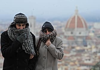 Un uomo e una donna si riparano dal freddo con sciarpe e cappelli a Firenze, 8 dicembre 2012. ANSA/MAURIZIO DEGL ' INNOCENTI