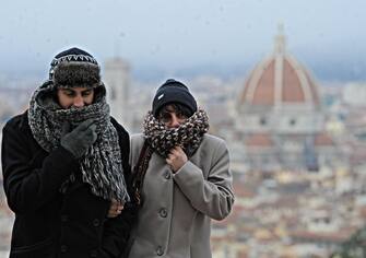 Un uomo e una donna si riparano dal freddo con sciarpe e cappelli a Firenze, 8 dicembre 2012. ANSA/MAURIZIO DEGL ' INNOCENTI
