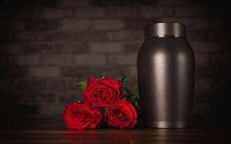 Funeral mourning urn next to a bunch of roses.