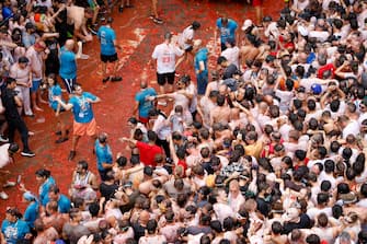 epa10828456 People participate in La Tomatina, a traditional and world-wide known tomato fight festival, in Bunol, Valencia province, eastern Spain, 30 August 2023. As every year on the last Wednesday of August, thousands of people visit the small village of Bunol to attend the Tomatina, a battle in which tons of ripe tomatoes are used to throw at each other.  EPA/MIGUEL ANGEL POLO