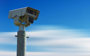 Closeup of a modern speed camera (traffic speed monitoring camera) against a clear blue sky in motion with copy space.