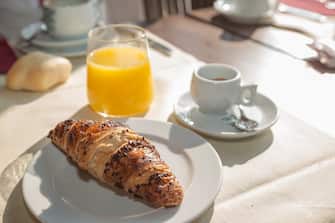 Typical italian breakfast, short black coffee, croissant and orange juice.
