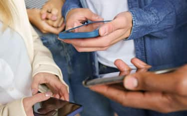 Hands of young unrecognizable people using smartphone.