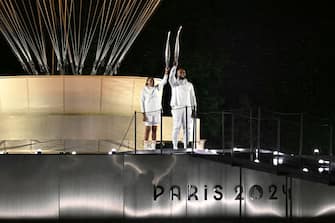 The torchbearers French former sprinter Marie-Jose Perec and French judoka Teddy Riner arrive to light the Olympic cauldron during the opening ceremony of the Paris 2024 Olympic Games in Paris on July 26, 2024. (Photo by MOHD RASFAN / AFP) (Photo by MOHD RASFAN/AFP via Getty Images)