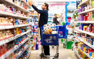 Full shopping cart, customer is stocking vital needs because of global chaos. Shopping with blur supermarket store products, interior background