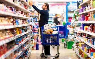 Full shopping cart, customer is stocking vital needs because of global chaos. Shopping with blur supermarket store products, interior background